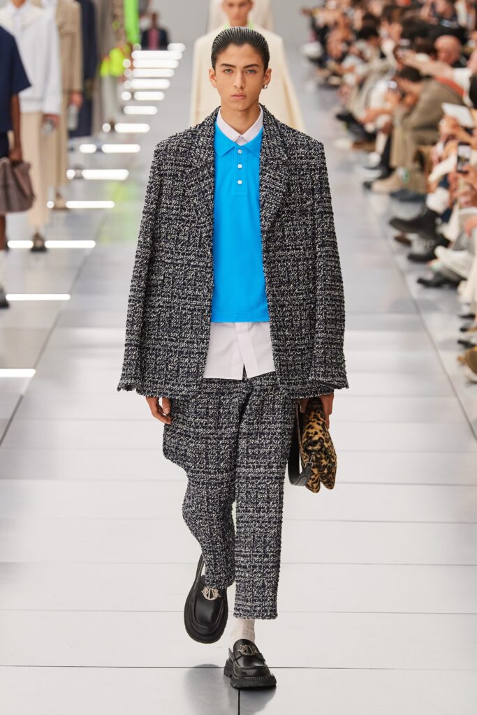 A relaxed black tweed jacket paired with blue cotton pants, featuring a collared design.