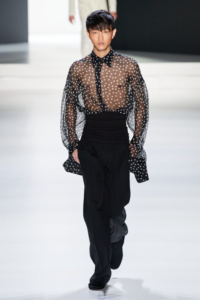A fitted black and white polka-dot shirt with long sleeves and a collared design.