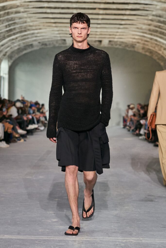 A relaxed black long-sleeve top with a collared design and an asymmetric skirt.