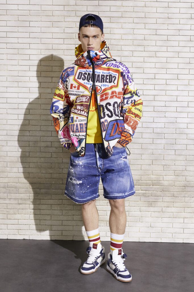 An oversized multicolor jacket paired with blue denim shorts, creating a bold streetwear look.