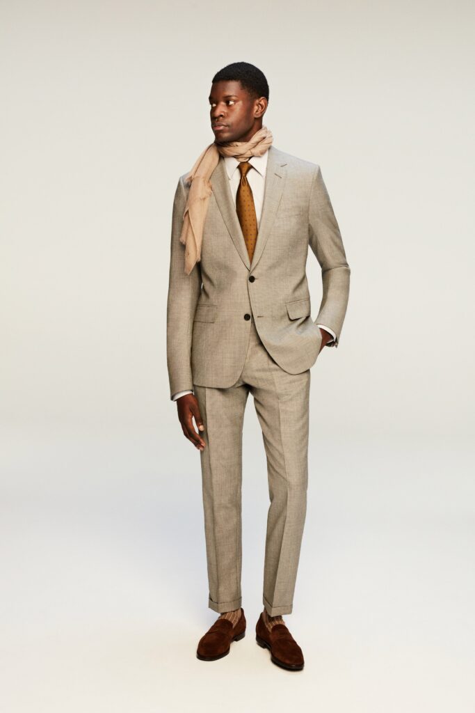 A tailored beige suit with long sleeves and a collared shirt, featuring a buttoned design.