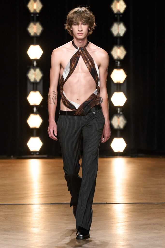 A fitted sleeveless top with an asymmetric design paired with black striped pants.