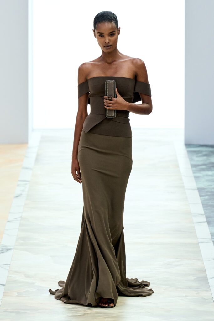 A fitted brown silk gown with an off-shoulder design and flared silhouette.