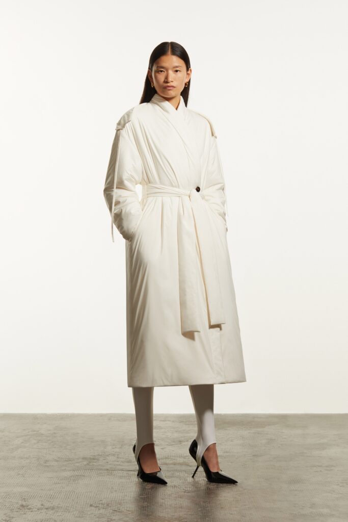 A relaxed white coat with long sleeves, a collared neckline, and a belted design.