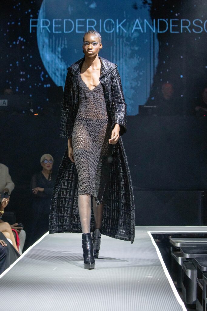 A fitted black mesh dress with a sleeveless design and layered coat over it.