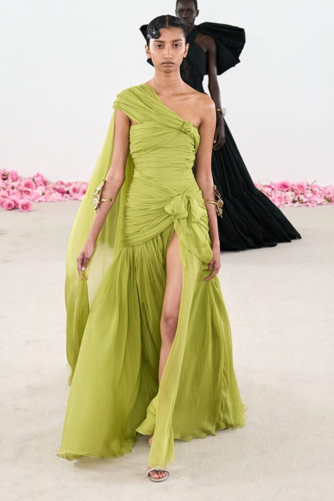 A fitted green silk sleeveless dress with an asymmetric design and a thigh-high slit.