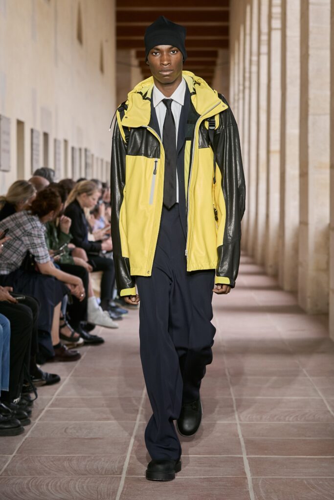 A relaxed black and yellow jacket with long sleeves and a collared design, paired with pants.