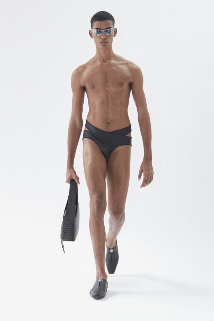 A fitted black neoprene swimsuit with a low-cut design and asymmetric details.