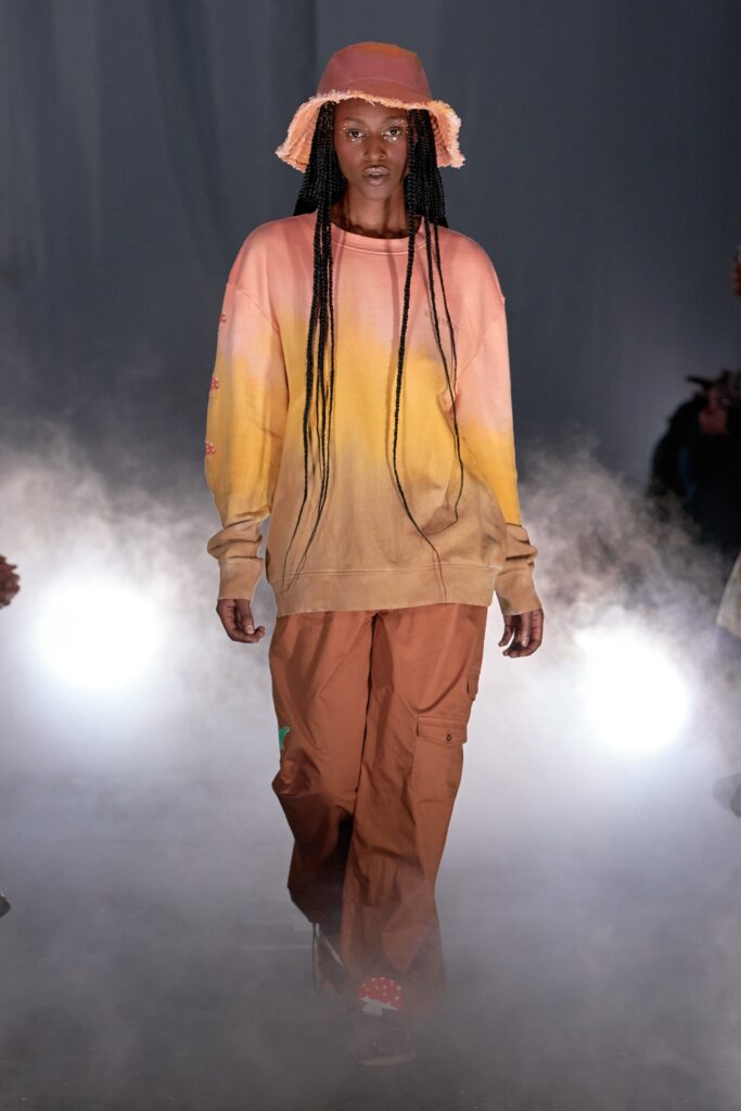 A relaxed long-sleeve ombre sweater paired with relaxed-fit pants in orange and pink hues.