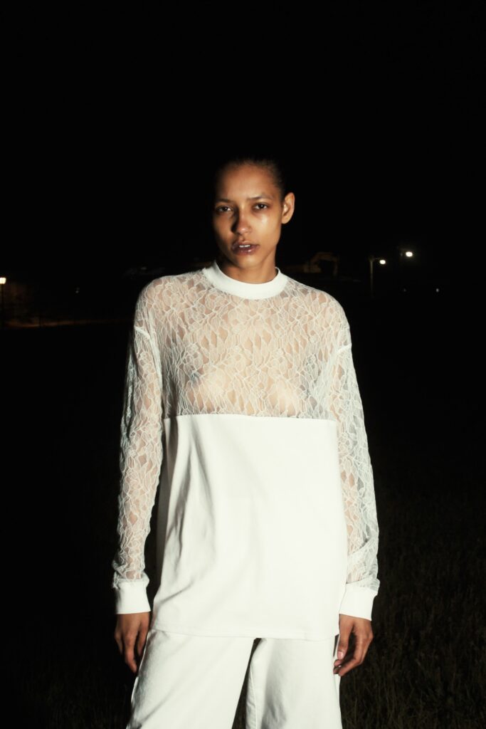 A relaxed white lace long-sleeve top paired with matching pants, featuring a sheer design.