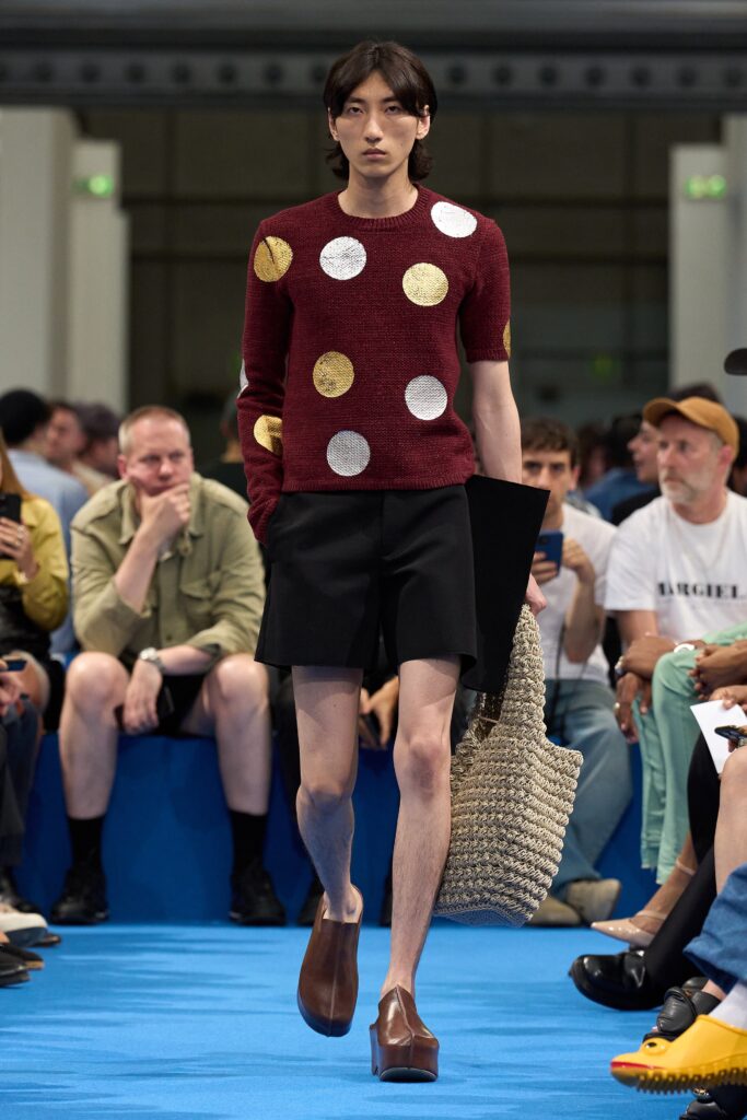 A fitted red polka-dot sweater paired with beige shorts for a stylish summer look.