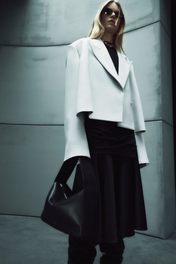 A fitted black dress paired with a long-sleeve white jacket featuring an asymmetric design.