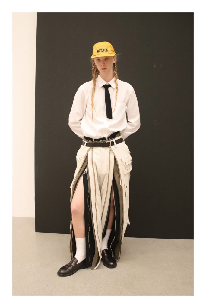 A white buttoned shirt paired with a beige asymmetric skirt featuring unique design elements.