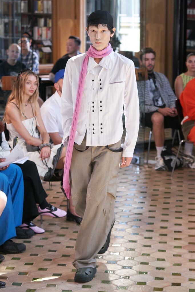 A relaxed white cotton long-sleeve shirt with a collared design paired with pleated beige pants.