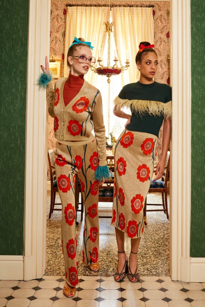 A fitted beige floral knit sweater paired with a matching skirt featuring vibrant red flowers.