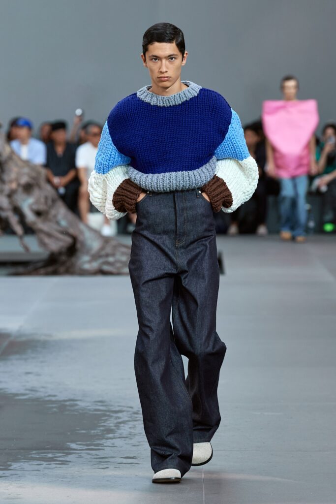 A relaxed blue cotton sweater with long sleeves paired with wide-leg denim pants.