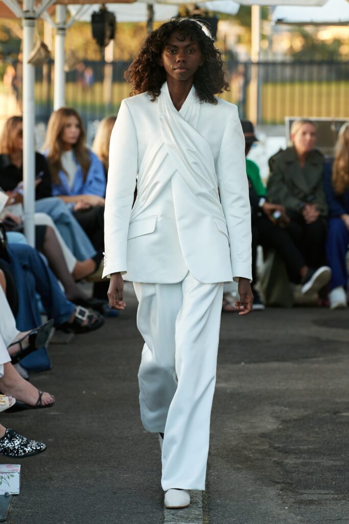 A tailored white suit with long sleeves and an asymmetric design detail.