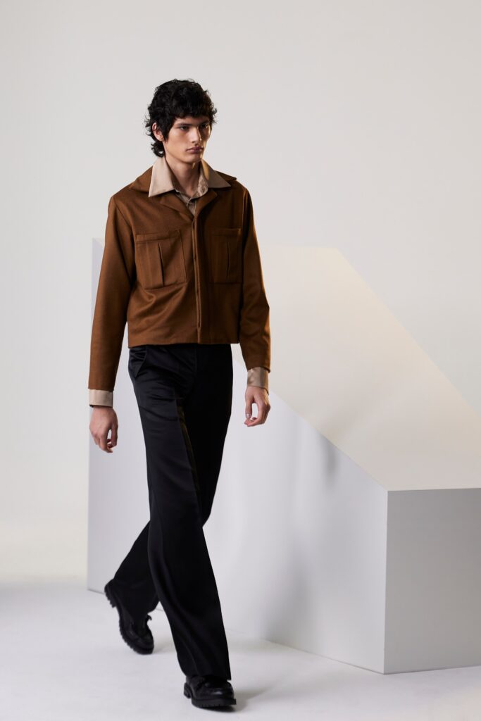 A fitted brown cotton jacket with a collared neckline paired with straight-leg black pants.