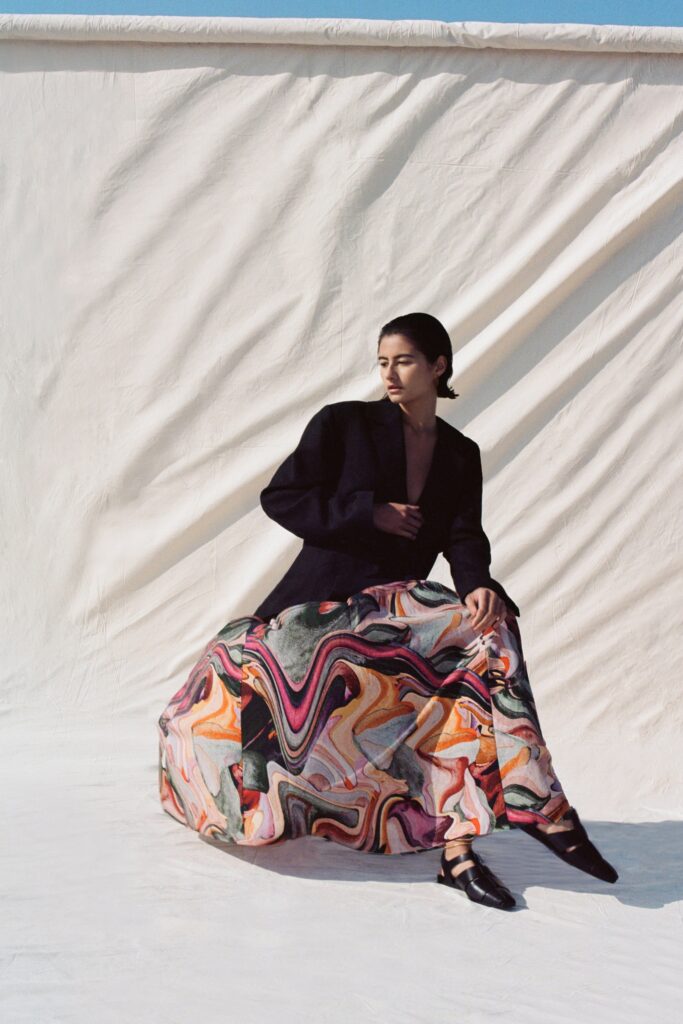 A relaxed black blazer paired with a printed multicolor skirt, featuring a long-sleeve and collared design.