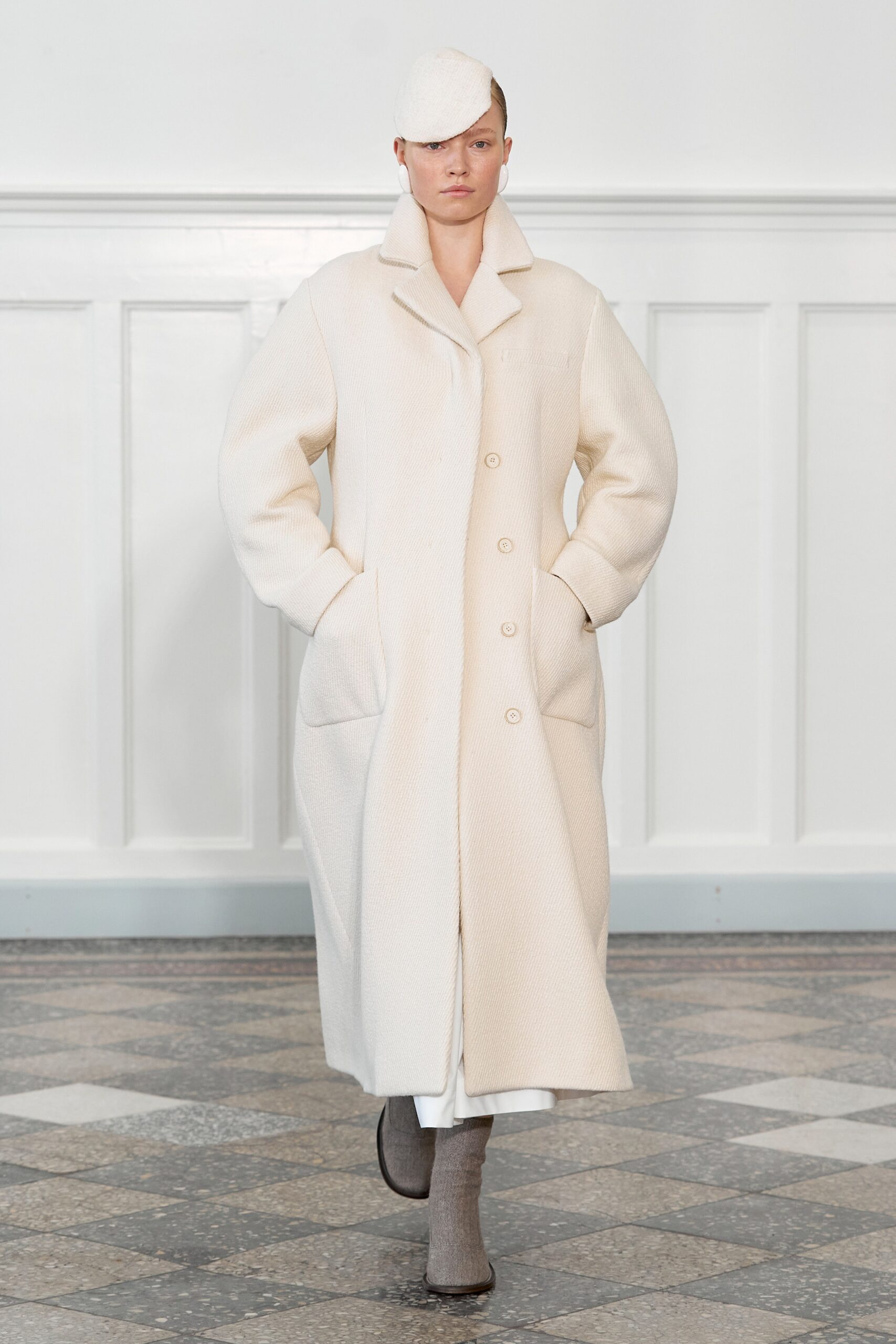 An oversized white wool coat with long sleeves and a collared design featuring button details.