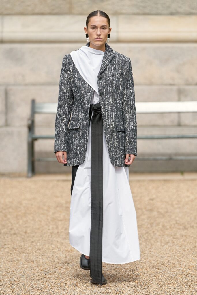 A fitted black and white layered dress with a collared long-sleeve jacket and asymmetric design.