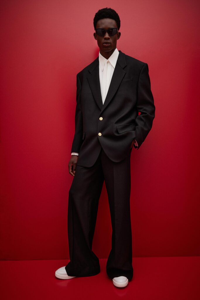 This relaxed black suit features a classic long-sleeve collared shirt paired with wide-leg trousers, creating a contemporary silhouette. The buttoned details add a touch of sophistication, while the overall fit exudes an effortless charm.