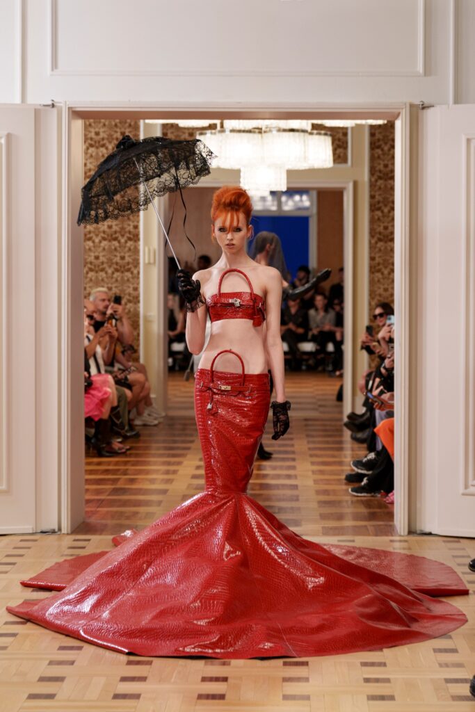 A fitted red silk strapless dress with a dramatic train and unique detailing.