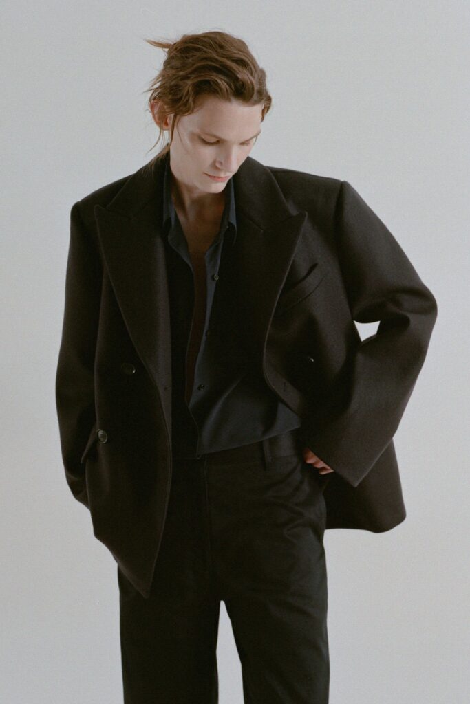 An oversized black wool jacket with a collared neckline and buttoned detail.