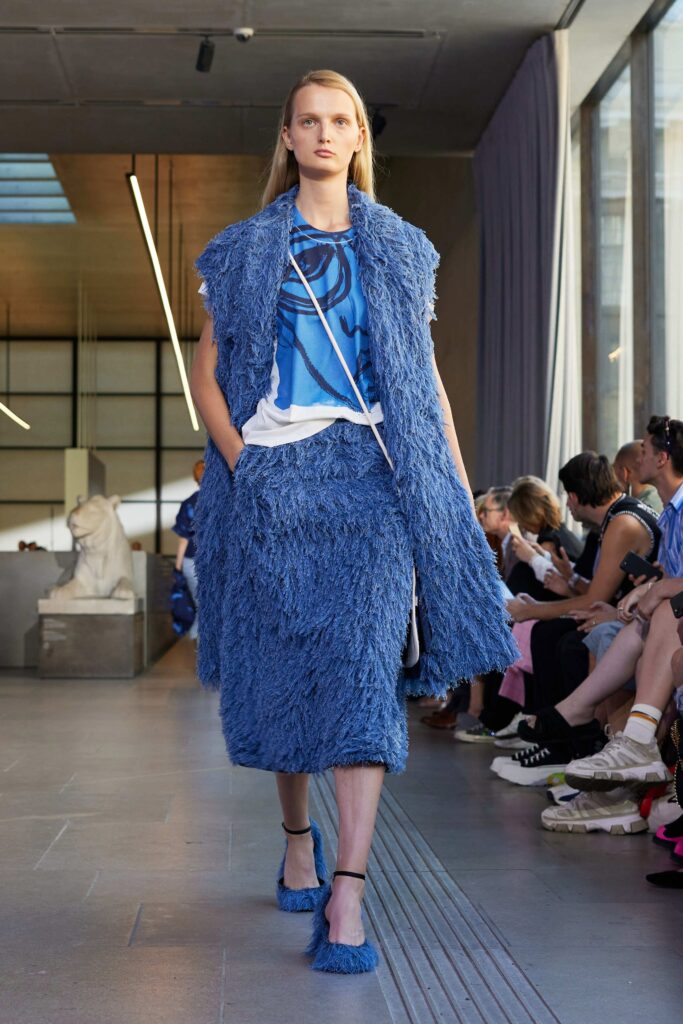 A fitted blue fringed coat paired with a matching skirt, creating a bold fashion statement.