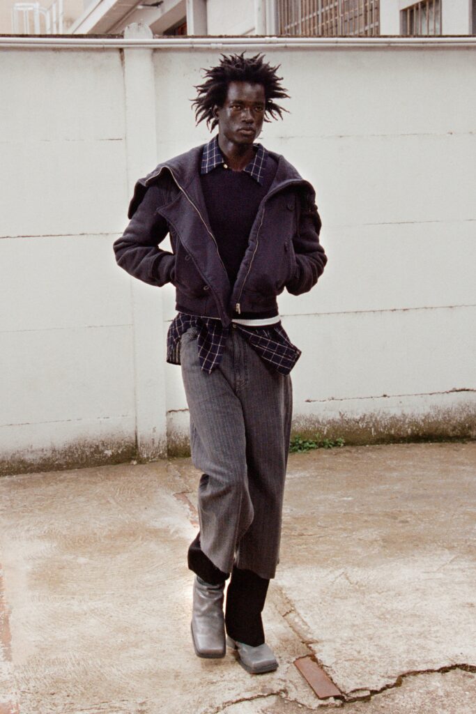 A relaxed black jacket paired with gray striped pants, featuring a layered look.