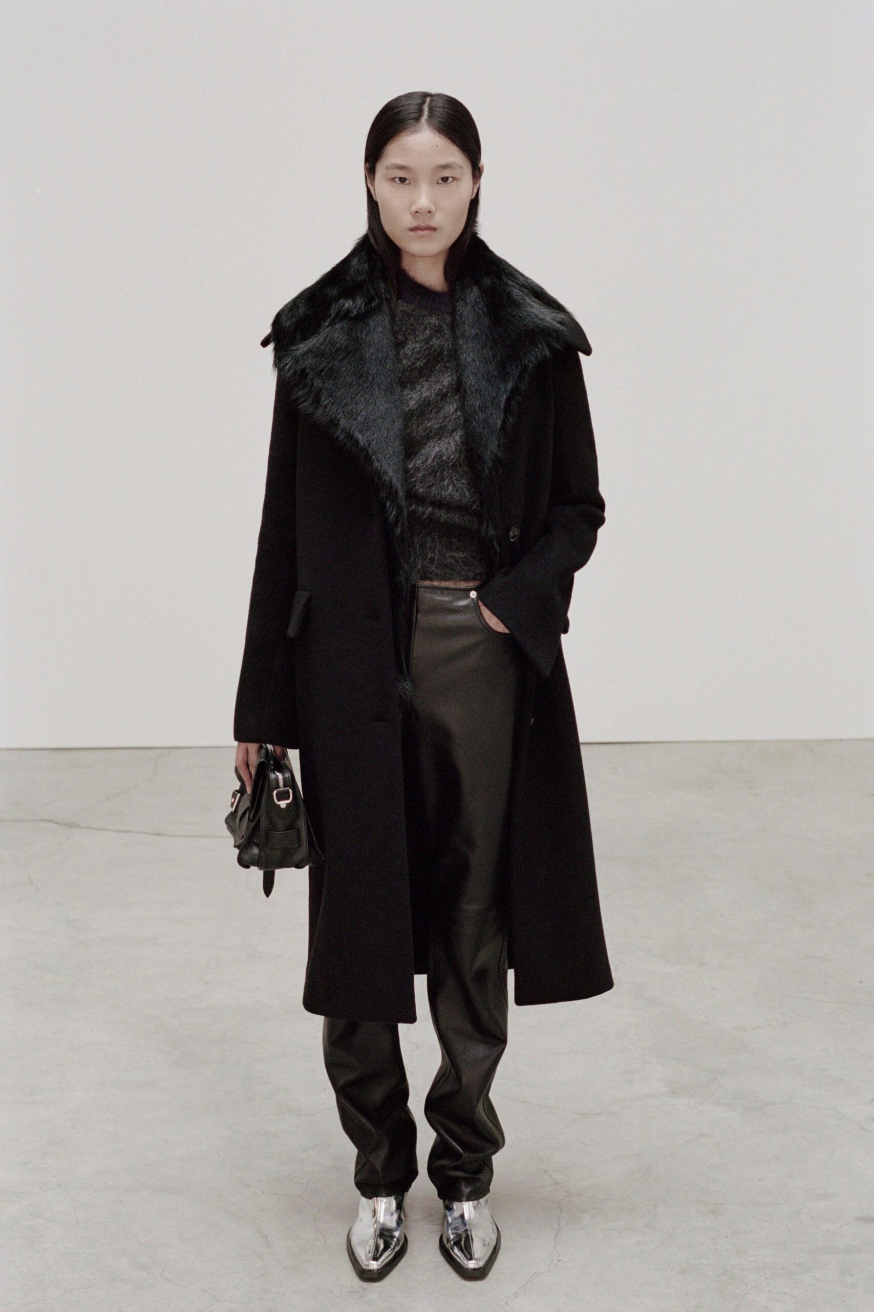 A fitted black leather coat with a collared neckline paired with straight-leg pants.