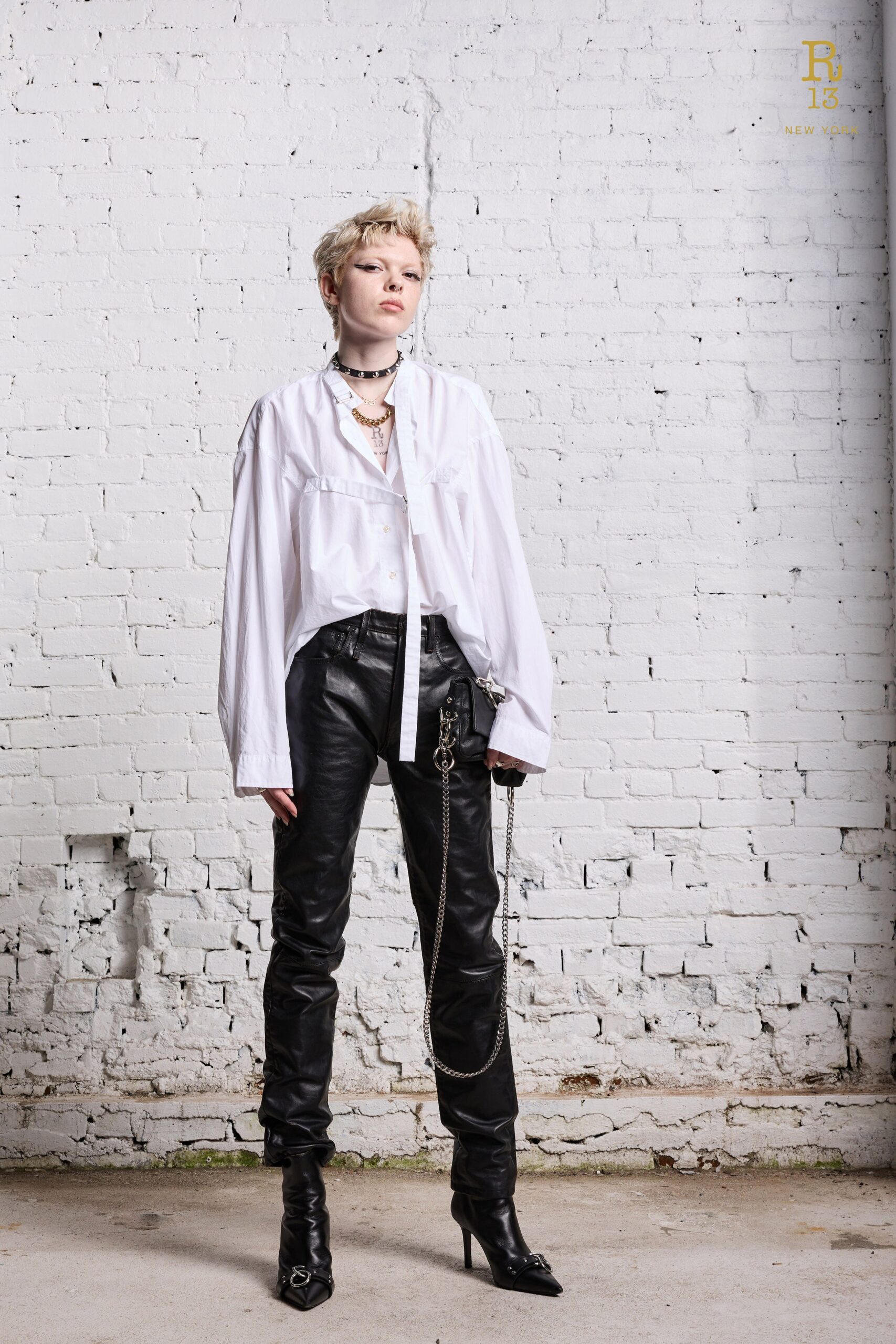 A relaxed white long-sleeve collared shirt paired with fitted black leather pants.