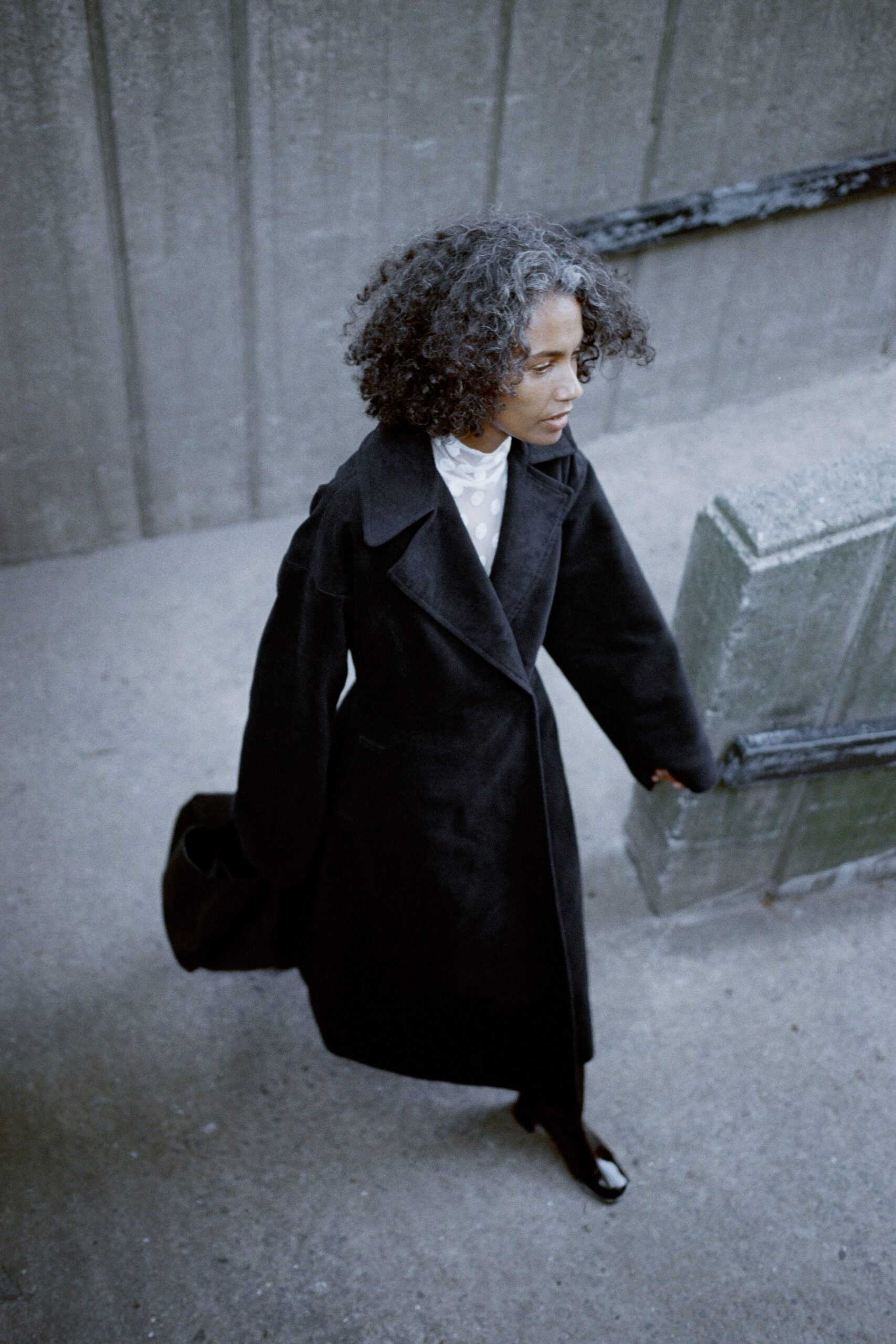 An oversized black wool coat with long sleeves and a collared design, featuring button details.