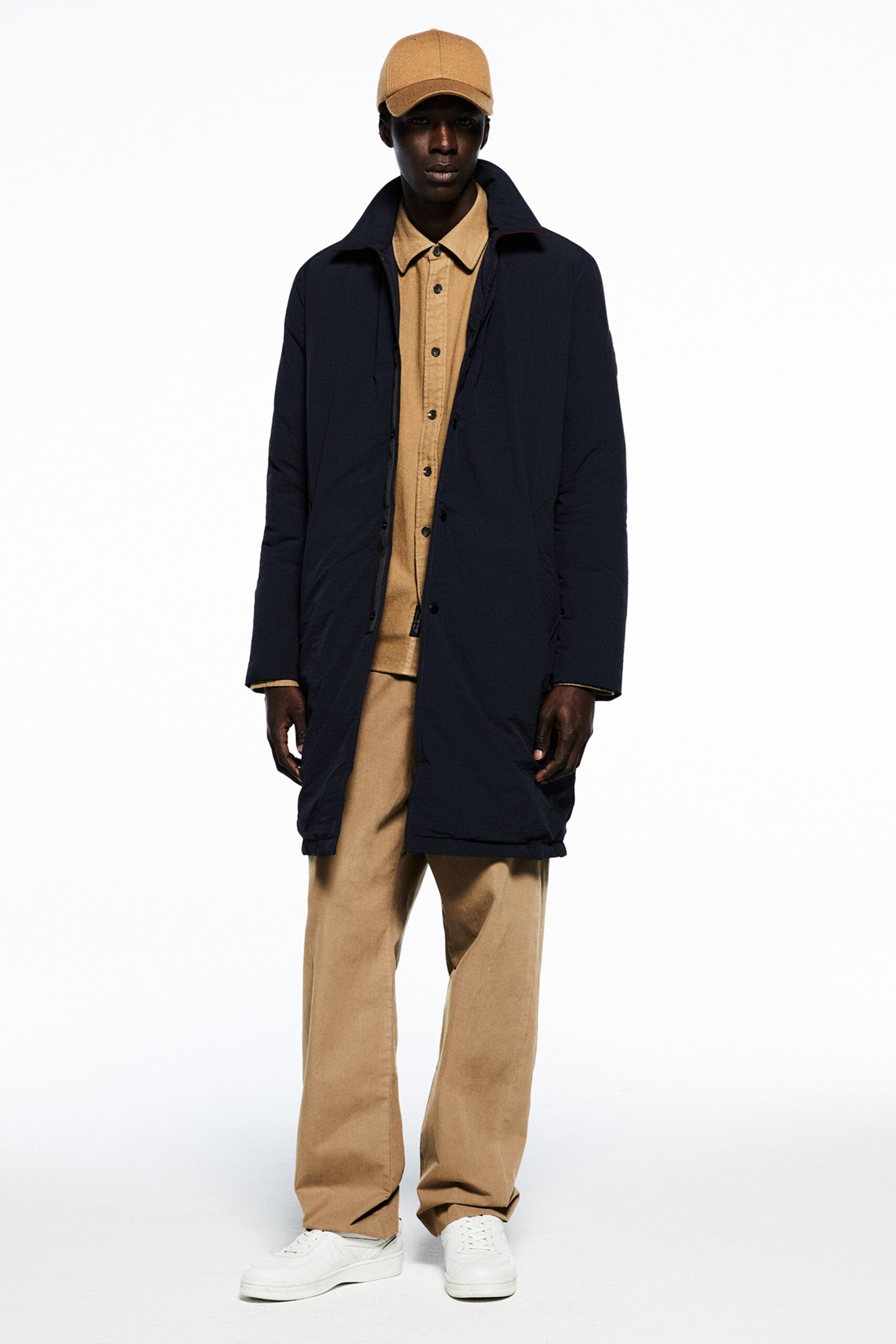 A relaxed navy coat paired with beige cotton pants and a collared long-sleeve shirt.