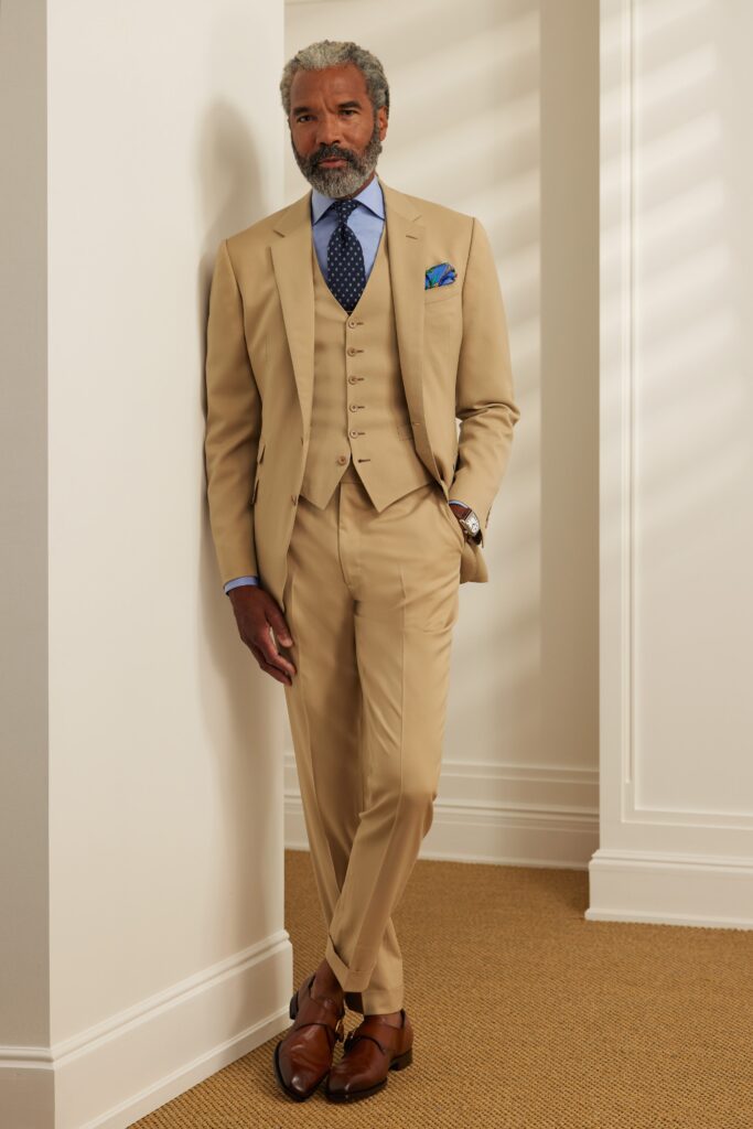 A tailored beige suit with a collared shirt and buttoned details for a sophisticated look.
