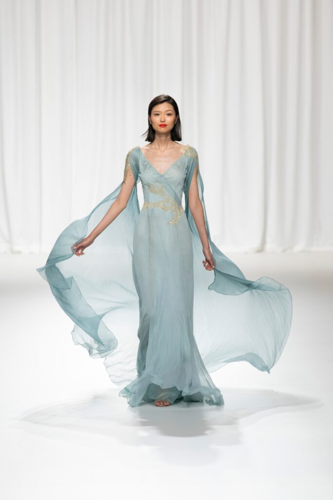 A fitted blue silk gown with short sleeves and a V-neckline, featuring a flowing silhouette.