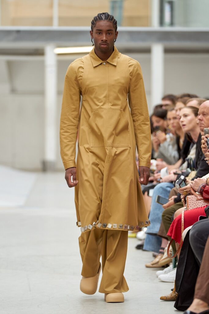 A relaxed beige cotton coat with long sleeves and a collared design, paired with matching pants.