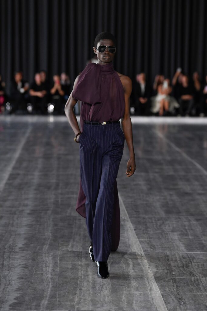 A fitted purple silk sleeveless top with an asymmetric design paired with fitted navy striped pants.