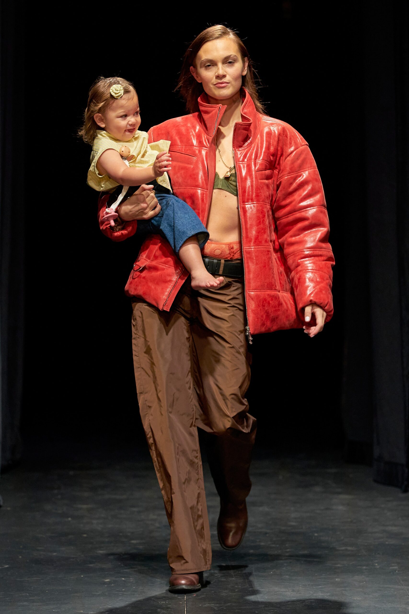A relaxed red leather jacket paired with brown pants, featuring a zippered design.