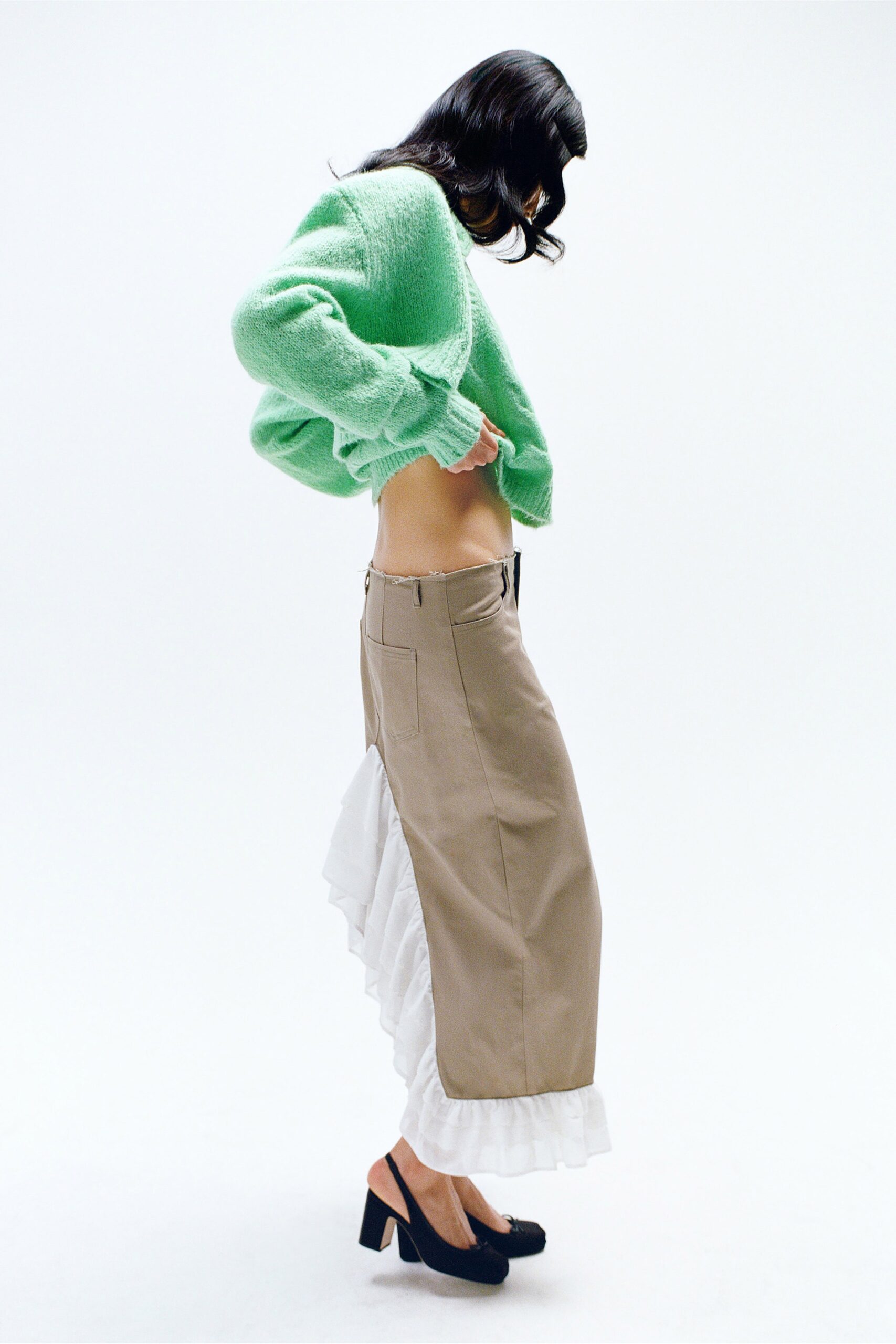 A relaxed green wool long-sleeve sweater paired with a layered beige skirt.