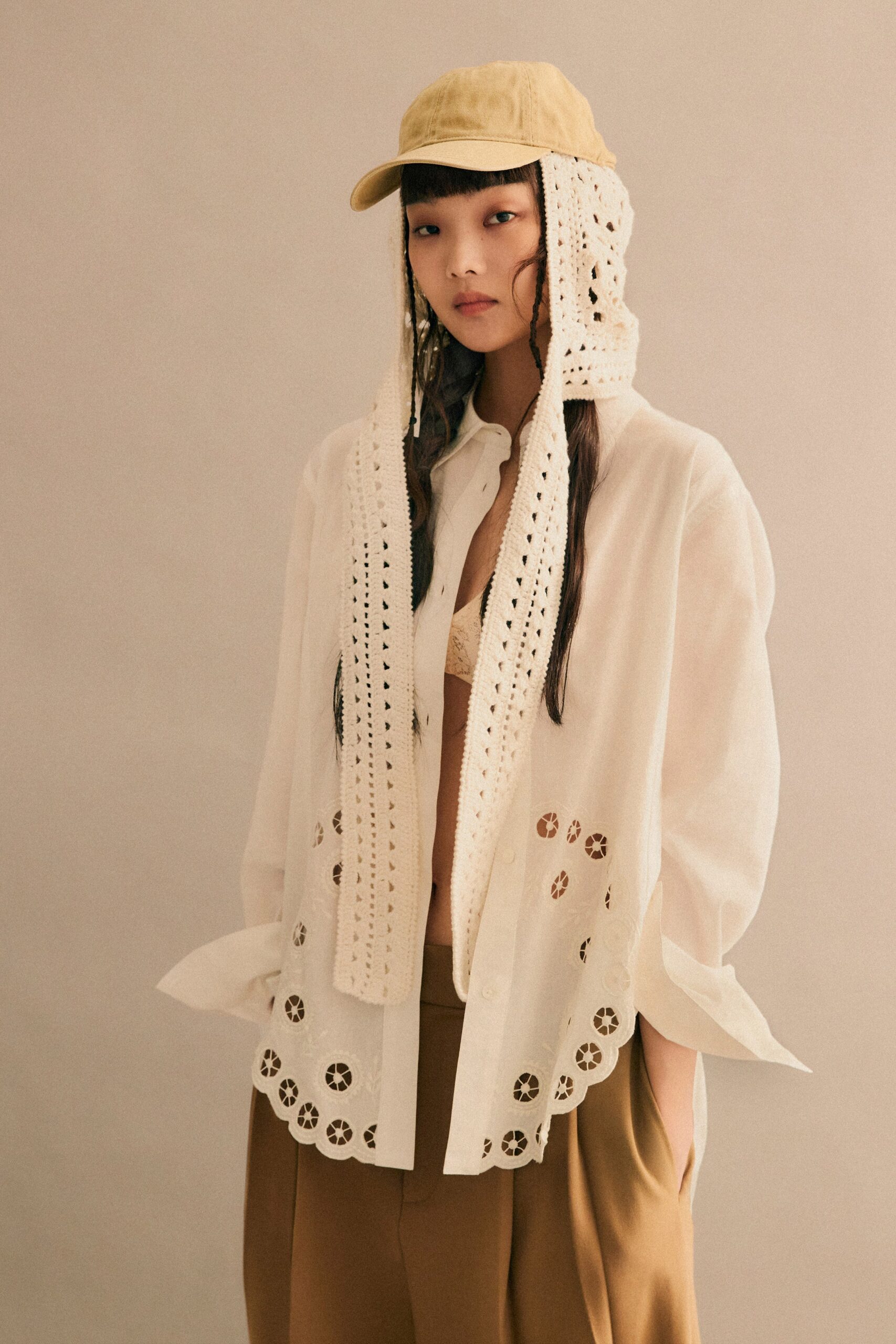 A relaxed white long-sleeve embroidered shirt paired with brown pants.