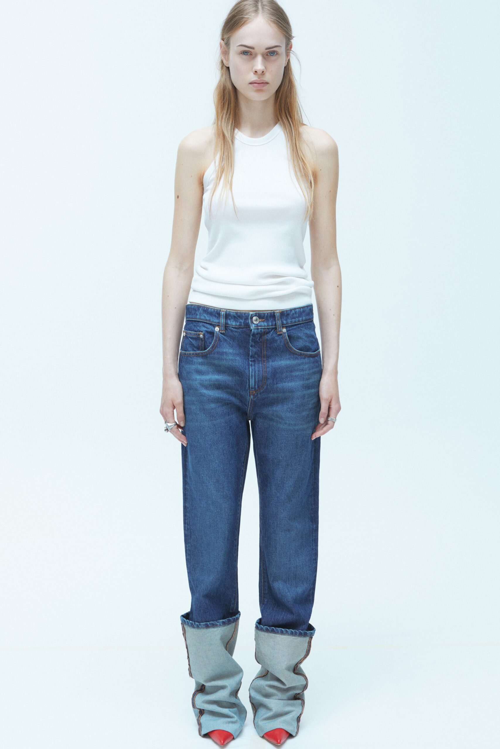 A relaxed white sleeveless top paired with straight-leg blue denim jeans.