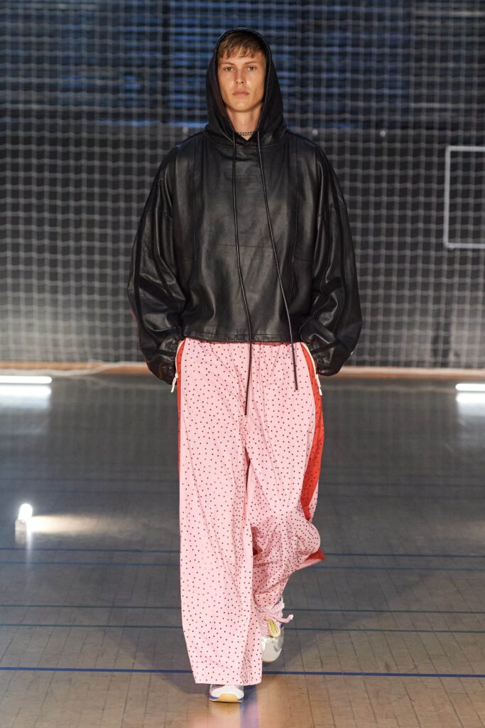 An oversized black leather hoodie paired with printed wide-leg pink pants for a stylish look.