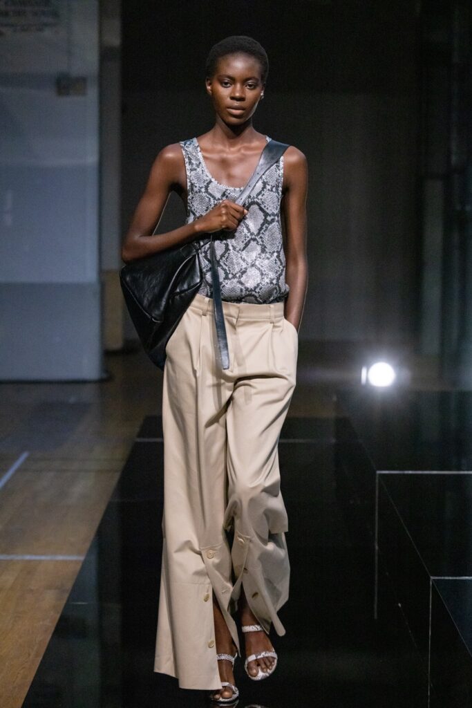 A relaxed gray printed sleeveless top paired with high-waisted beige wide-leg pants.