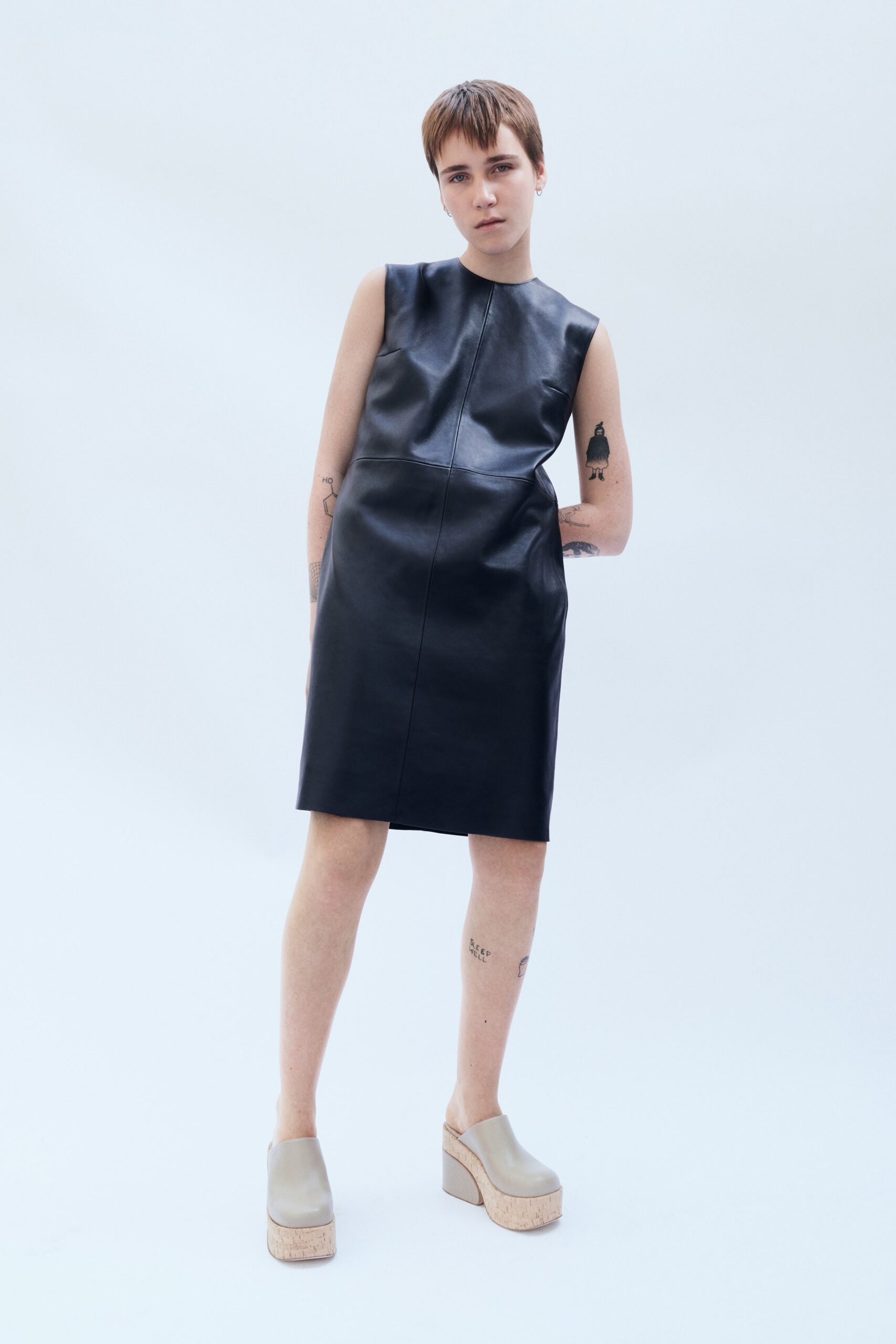 A fitted black leather sleeveless dress with a high neckline and straight silhouette.