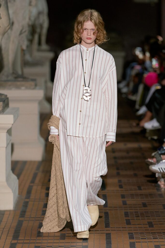 A relaxed-fit white striped shirt paired with beige pants, featuring a collared neckline.