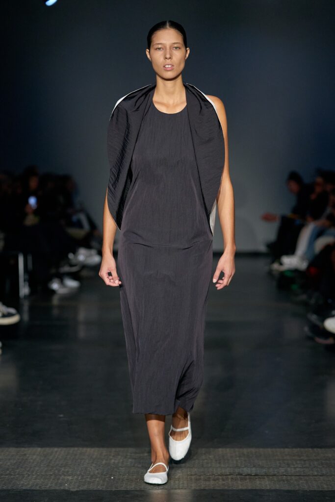 A relaxed black cotton dress with a high neckline and straight-leg silhouette.