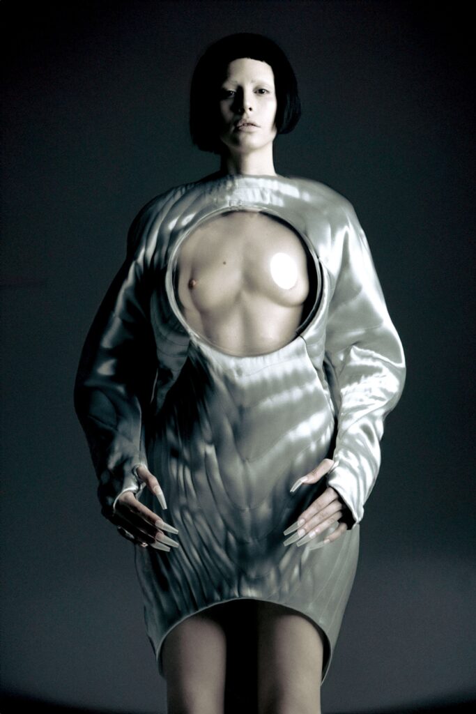 A fitted white silk dress with long sleeves and an asymmetric design detail.