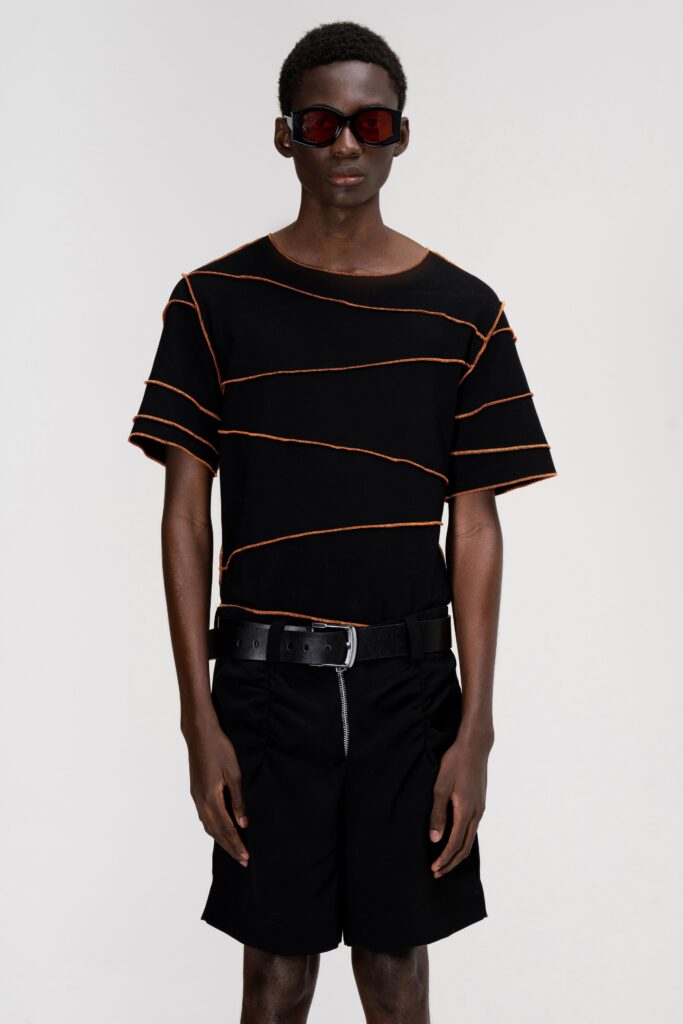 A relaxed black cotton top with orange stripes paired with black shorts.