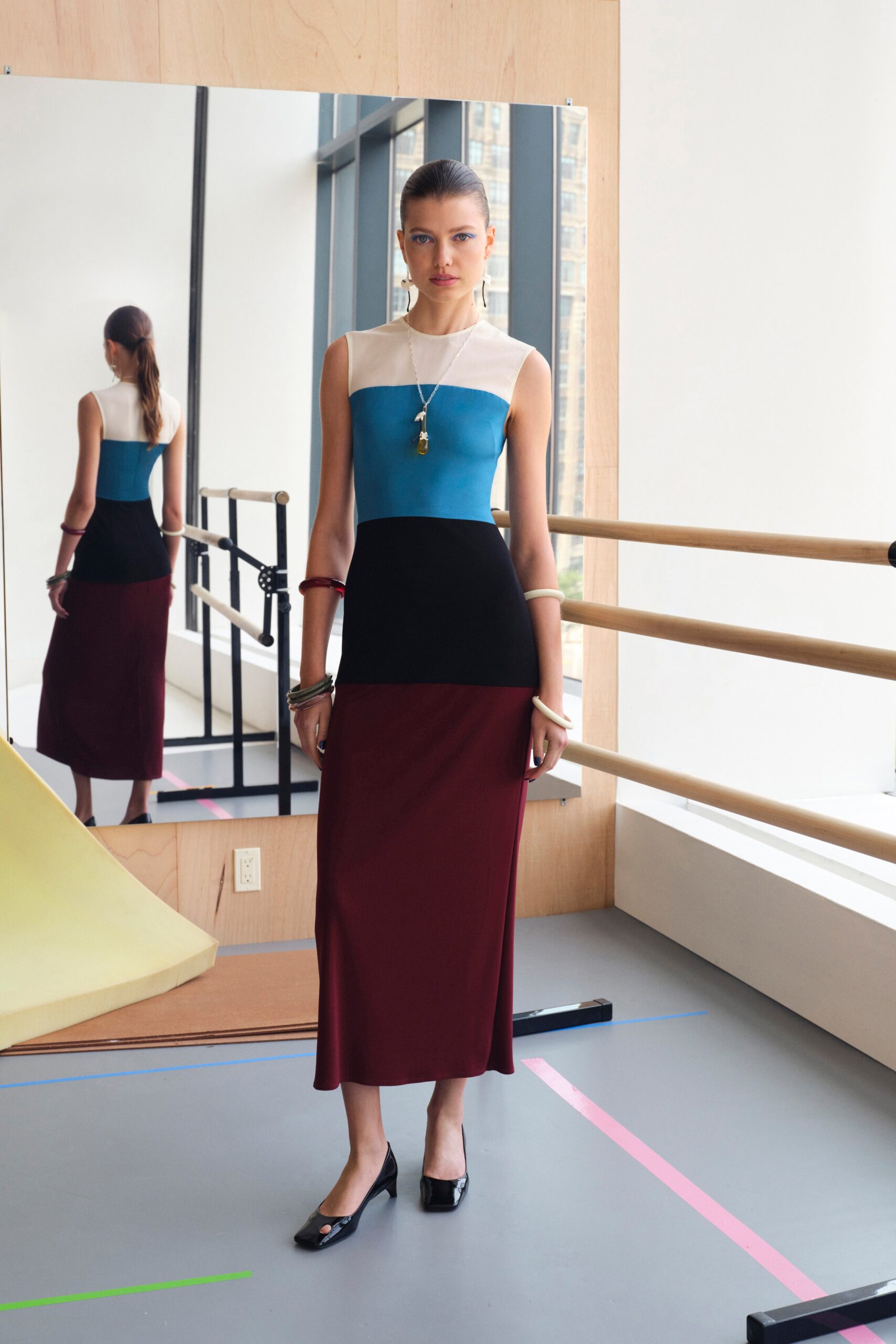 A fitted sleeveless dress featuring a color-blocked design in blue, black, and burgundy.